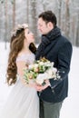 Winter wedding, stylish young couple, bride and groom, in the forest, tender hugs. Bride with long hair in cotton wreath Royalty Free Stock Photo