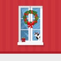 Winter window with view, a present and a cat on the sill. Christmas wreath. Cozy home. Merry Christmas and Happy New Royalty Free Stock Photo
