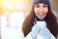 Winter young woman portrait. Beauty Joyful Model Girl holding thermocup with hot tea and smiling, having fun in winter