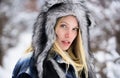 Wintertime. Closeup portrait of blonde girl in stylish fur hat in snowy winter day. Beautiful young woman in plaid coat Royalty Free Stock Photo