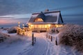 Wintertime cozy thatched cottage near to beach. Decorated with lights. AI generated Royalty Free Stock Photo