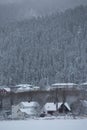 Wintertime and snowy forest with wooden houses Royalty Free Stock Photo