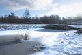 A wintery scene showing a snow covered bridge over a frozen river