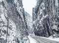 Wintery snowcovered mountain road with white snowy spruces and rocks. Wonderful wintry landscape. Travel background. Royalty Free Stock Photo