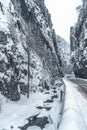 Wintery snowcovered mountain road with white snowy spruces and rocks. Wonderful wintry landscape. Travel background.