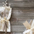 Wintry Christmas Table Place Setting with Snowflake napkin, Silver present with white bow and berries, all on rustic wood boards b Royalty Free Stock Photo