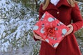 Wintry image of young woman wearing red coat and holding wrapped present