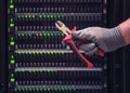 Wire cutters in the hands of a man at the server for data storage, close-up Royalty Free Stock Photo