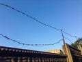 A wire fence with barbed wire is hanging over a wall Royalty Free Stock Photo