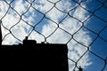 Wire fence behind blue sky with clouds Royalty Free Stock Photo