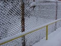 Wire fence in the snow. Metallic net with snow. Metal net in winter covered with snow. Wire fence closeup. Steel wire mesh fence