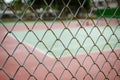 Wire fence with tennis court on background Royalty Free Stock Photo