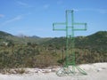 Discarded wire framed cross with hills and mountains in the background.