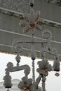 A wire and glass flower windchime covered in snow hanging from a pergola