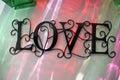 wire LOVE sign with colorful light reflections from sunlight from colored bottles Royalty Free Stock Photo