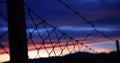 Wire mesh fence on silhouettes of poles on sky blur background at sunset Royalty Free Stock Photo