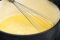 Wire whisk in a pot with golden yellow semolina flummery or pudding, cooking a delicious dessert, copy space, selected focus Royalty Free Stock Photo