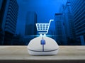 Wireless computer mouse with online shopping icon on wooden table in front of city tower background, Shopping online concept Royalty Free Stock Photo