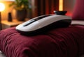 Wireless computer mouse resting on a plush red cushion in a cozy indoor setting Royalty Free Stock Photo
