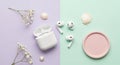 Wireless earbuds and an open charging case are placed on a split pastel background of purple and Royalty Free Stock Photo