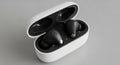 Wireless earbuds resting in an open charging case on a gray surface Royalty Free Stock Photo