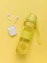 Wireless headphones and a transparent yellow bottle with lemon and ice Royalty Free Stock Photo