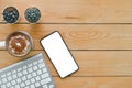 Wireless keyboard Mobile phone Cactus and hot cappuccino Resting on a brown wooden office desk Shot from a high angle Royalty Free Stock Photo