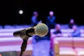 Wireless microphone on the stand. Blurred background. People in the audience. Show on stage in the theater or concert hall