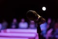 Wireless microphone on the stand. Blurred background. People in the audience. Show on stage in the theater or concert hall