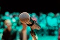 Wireless microphone on the stand. Blurred background. People in the audience. Show on stage in the theater or concert hall