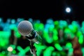 Wireless microphone on the stand. Blurred background. People in the audience. Show on stage in the theater or concert hall