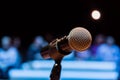 Wireless microphone on the stand. Blurred background. People in the audience. Show on stage in the theater or concert hall