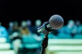 Wireless microphone on the stand. Blurred background. People in the audience. Show on stage in the theater or concert hall