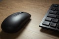 Wireless mouse and keyboard set on top of a wooden office desk, on a workstation