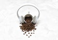 Wireless overhead headphones on a coffee cup and roasted coffee beans scattered on a textured concrete table