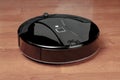 wireless robotic vacuum cleaner on laminate floor close up view. modern smart cleaning technology housekeeping Royalty Free Stock Photo