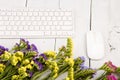 Wireless slim keyboard, mouse and colorful flowers on white wood