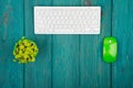 Wireless slim white keyboard and green mouse on blue wooden desk