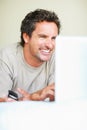 Wireless surfing. Portrait of smiling mature man with cellphone using laptop. Royalty Free Stock Photo