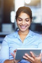 Wireless technology always gives her a reason to smile. a happy young businesswoman using a tablet while sitting at her Royalty Free Stock Photo