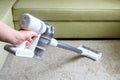 Wireless vacuum cleaner used on carpet in room. Housework with new white hoover. Person holds modern vacuum cleaner by sofa Royalty Free Stock Photo