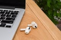 Wireless white headphones `airpods` near the laptop Royalty Free Stock Photo