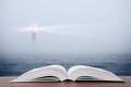 Wisdom concept - open book over sea and lighthouse background Royalty Free Stock Photo
