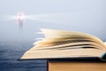 Wisdom concept - open book over sea and lighthouse background