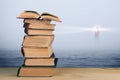 Wisdom concept - stack of books over sea and lighthouse background