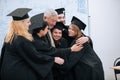 A wise elderly university professor rejoices together with his students in robes and hats at the end of their studies Royalty Free Stock Photo