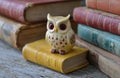 Wise owl figurine perched on book with stack of old books in background Royalty Free Stock Photo