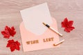 Wish list. Blank paper for writing in an envelope, fountain pen and maple leaves on a wooden background. Top view Royalty Free Stock Photo