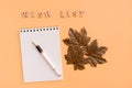 Wish list. Notepad, fountain pen and maple leaves on a yellow background. Top view Royalty Free Stock Photo