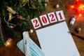 wish sheet on a wooden background with the numbers 2021, a blank sheet of paper, mask, syringe, covid-19 vaccine, led is a garland Royalty Free Stock Photo